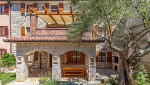 A stone building with wooden balconies, a covered outdoor seating area, and a tree in the foreground. - 4 bedroom pet friendly home in Medulin (Medulin)