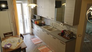Une cuisine moderne avec des meubles en bois, un four à micro-ondes encastré et un évier. On y trouve une table à manger avec des chaises et un tapis.