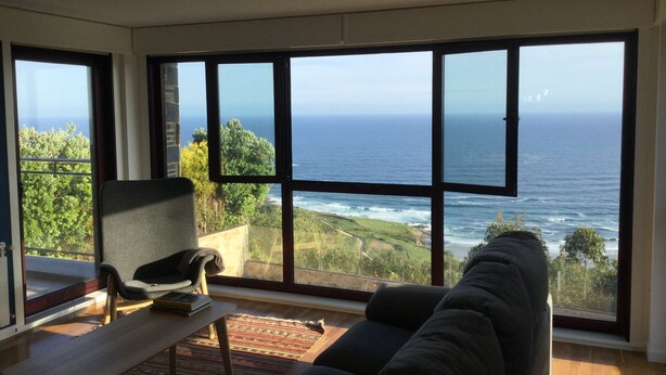 Ein großzügiges Wohnzimmer mit einem großen Fenster mit Meerblick.