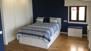 Ein Schlafzimmer mit einem Bett, einem Kleiderschrank, einer Bank und einem Fenster.