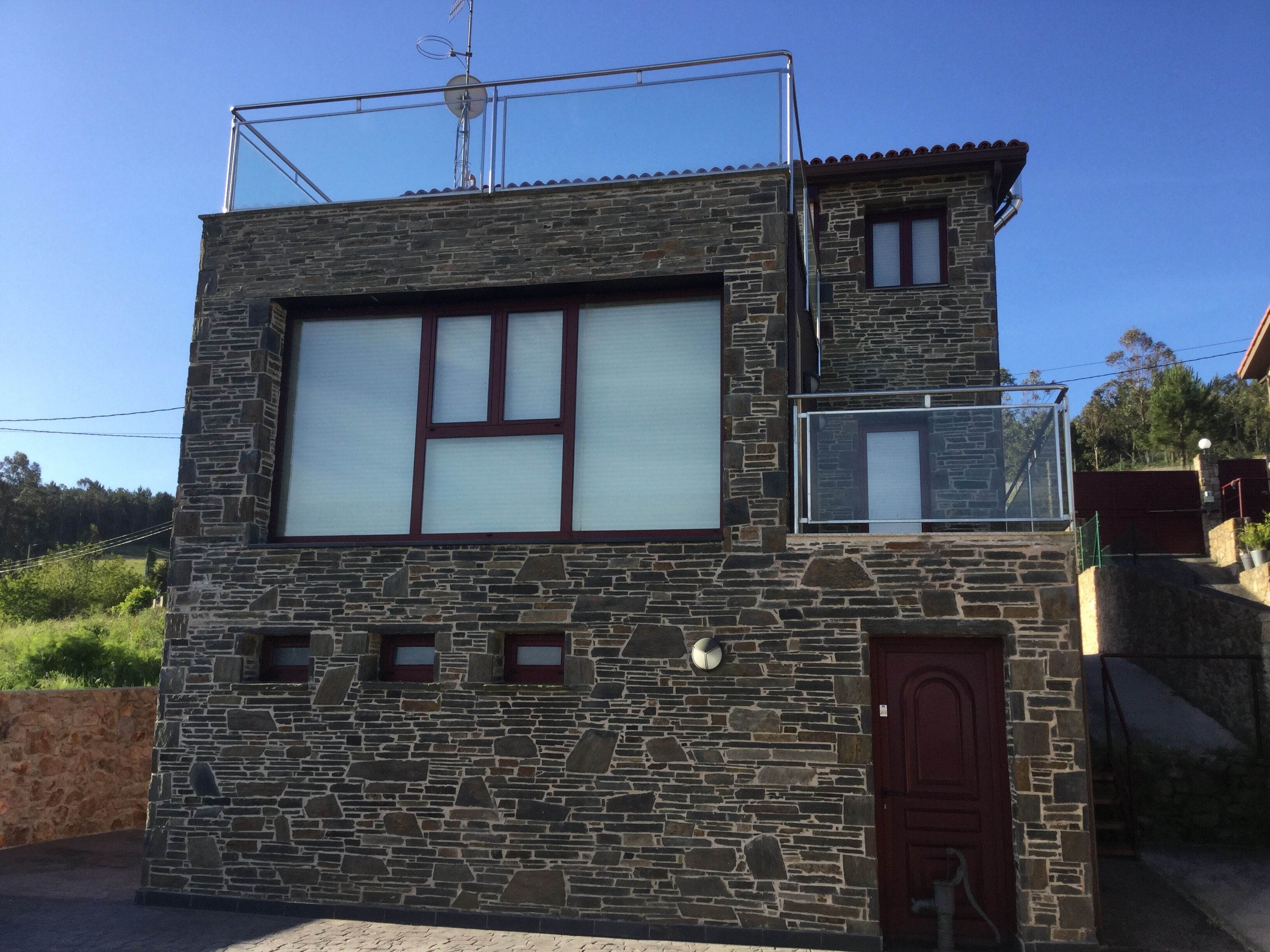 A stone building with a large window, a small balcony, and a door.