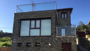 Ein Steinhaus mit einem großen Fenster, einem kleinen Balkon und einer Tür.