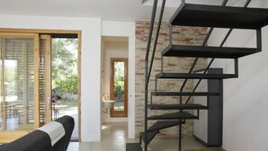 Un intérieur moderne avec un escalier en colimaçon noir, un banc en bois et une vue sur l’extérieur.