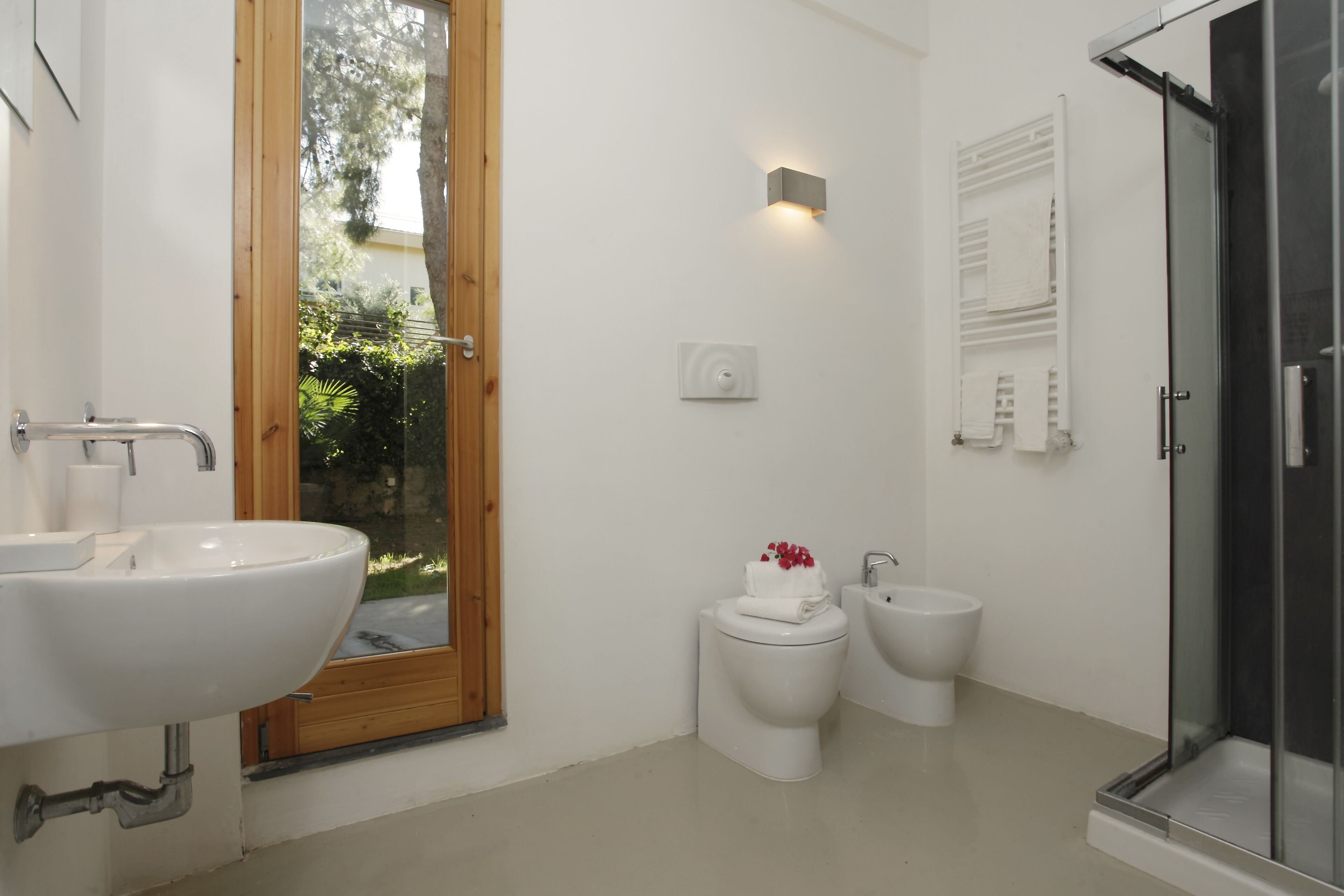 Une salle de bain moderne dotée d’un grand lavabo, de toilettes, d’un bidet et d’une douche à parois de verre.