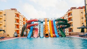 Ein Schwimmbecken mit mehreren Wasserrutschen vor einem mehrstöckigen Gebäude.
