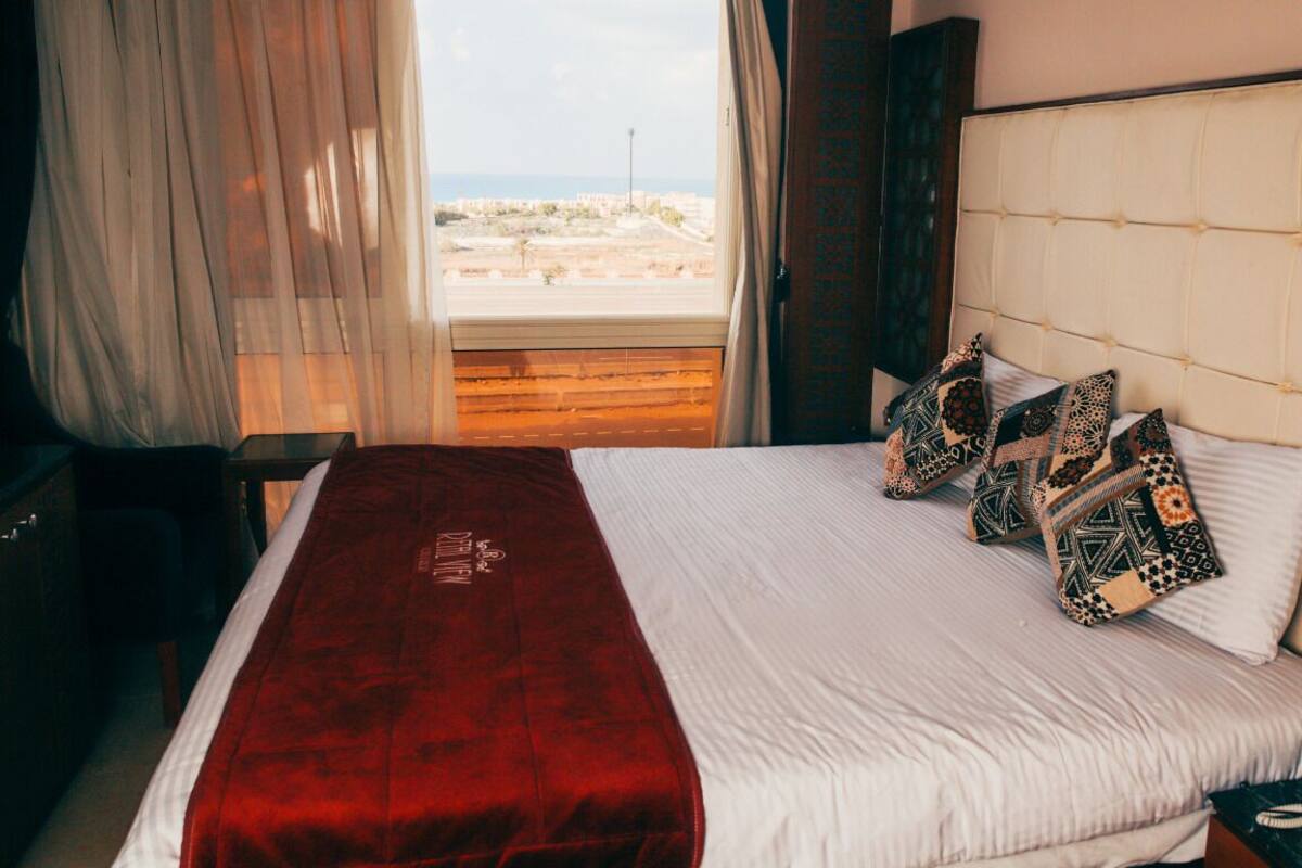Ett hotellrum med en säng, en telefon och utsikt över omgivningarna.
