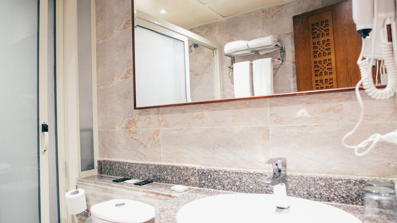 Une salle de bain moderne avec un comptoir en marbre, un lavabo, des toilettes et un grand miroir.