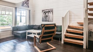 A modern living room with a wooden floor, a grey sofa, a white coffee table, and a wooden chair. There is a staircase with wooden steps and a white railing. - Gorgeous home in Søre Osen with WiFi (Søre Osen)