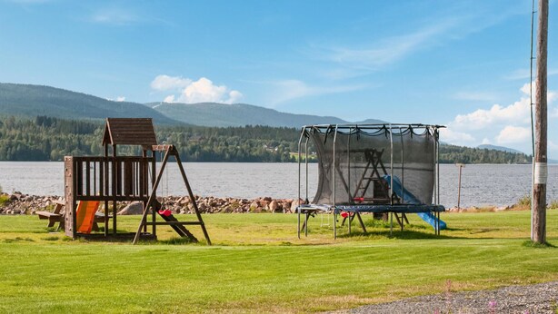 A playground with a swing set and a slide, a wooden bench, and a metal structure with a net. - Gorgeous home in Søre Osen with WiFi (Søre Osen)