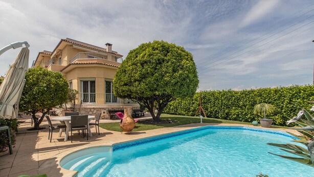 A swimming pool with a curved edge, surrounded by a patio area with outdoor furniture and a large tree. - Apartment panoramic view Baie des Anges (Nice)