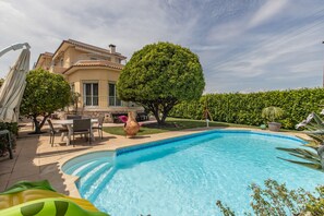 A swimming pool with a curved edge, surrounded by a patio area with outdoor furniture and a large tree. - Apartment with a panoramic view of Baie des Anges (Nice)