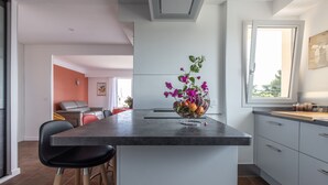 A modern kitchen with a central island, bar stools, and a flower vase. - Apartment panoramic view Baie des Anges (Nice)
