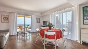 A spacious living area with a dining table set for four, a sofa, and a TV. - Apartment panoramic view Baie des Anges (Nice)