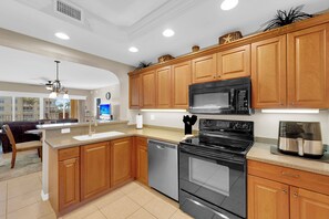 A modern kitchen with wooden cabinets, a microwave, stove, and dishwasher. - Vacation In Style At A Great Price!  Bella Lago Deluxe 2B/2B w/ Den Condo Steps From Beach! (Fort Myers Beach)