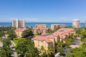 A coastal resort with multiple buildings, a clear view of the ocean, and lush greenery. - Vacation In Style At A Great Price!  Bella Lago Deluxe 2B/2B w/ Den Condo Steps From Beach! (Fort Myers Beach)