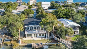 A coastal residential area with houses, a large house with a balcony, and a body of water.