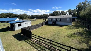 A fenced property with a small building, a covered structure, and a grassy area.