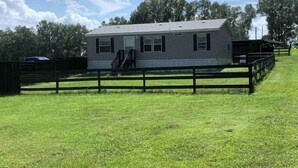 A single-story house with a front porch and a fenced yard.