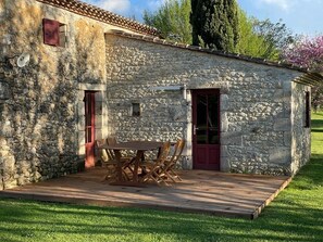 A stone building with a wooden deck and a table with chairs.