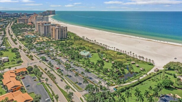 Ein Küstenresort mit Strand, einer von Palmen gesäumten Uferpromenade und Hochhäusern.