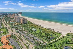 A coastal resort with a beachfront, palm-lined promenade, and high-rise hotels. - Tastefully Designed, 1st Floor Corner Condo, Steps from the Beach! (Marco Island)
