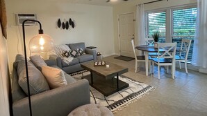 Ein Wohnzimmer mit einer Couch, einem Couchtisch und einem Essbereich mit Stühlen.
