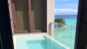 Un balcón con vistas despejadas a una piscina turquesa y al océano.