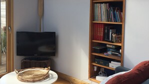 A cozy living room with a television, a bookshelf, a wicker table, and a blue sofa.