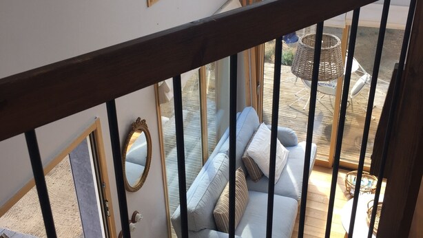 A room with a balcony, a sofa, a small round table, and a mirror.