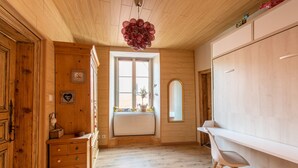 Un intérieur en bois avec un radiateur, une chaise blanche et un grand miroir.