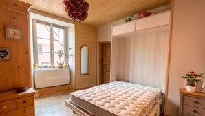 Une chambre à coucher avec un lit, une commode en bois et une fenêtre donnant sur un beau paysage.