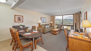 Ein Hotelzimmer mit Essbereich, einer Sitzecke, einem Schreibtisch und einem großen Fenster mit Blick auf die Stadt.