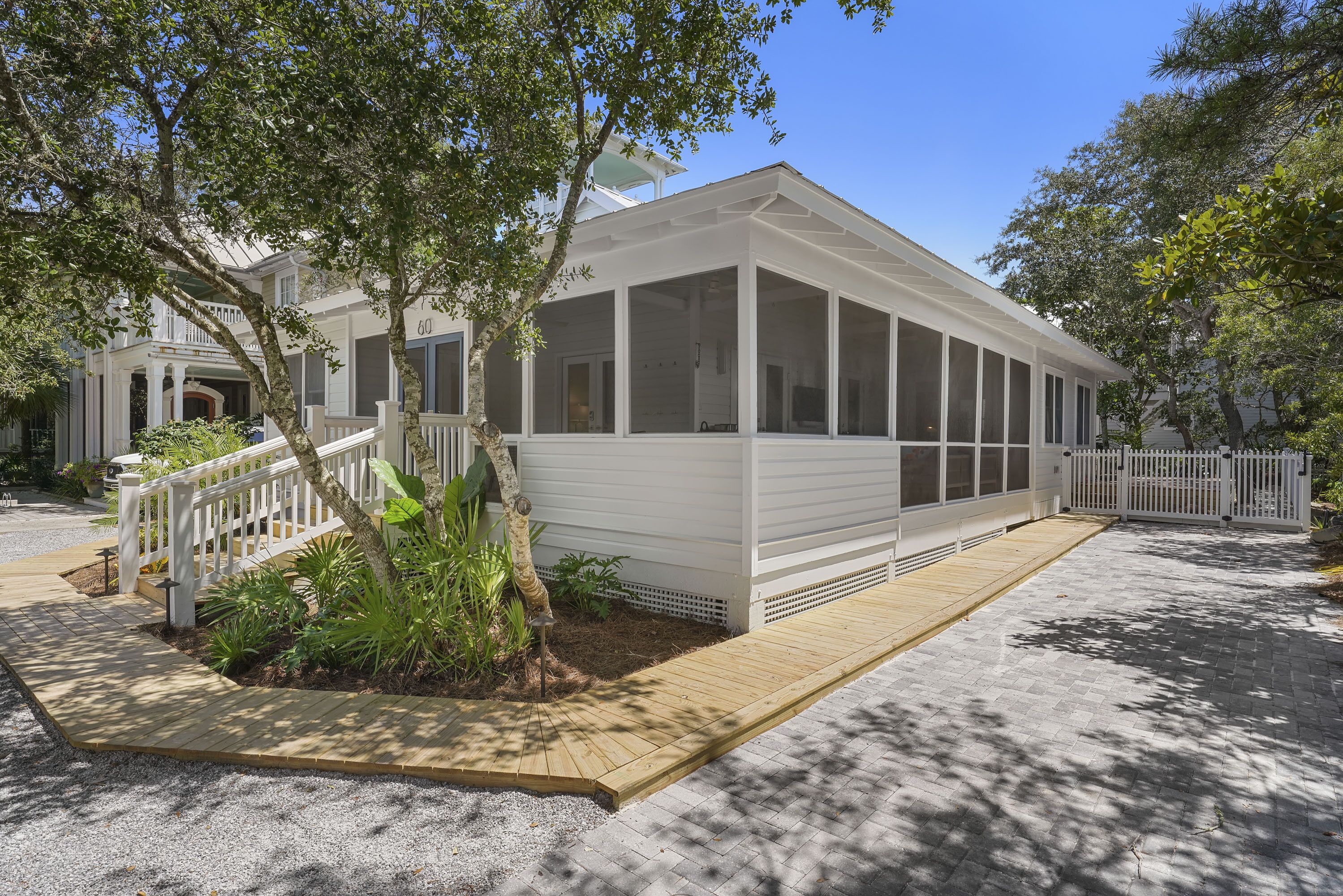 A white building with a covered porch and a wooden deck.