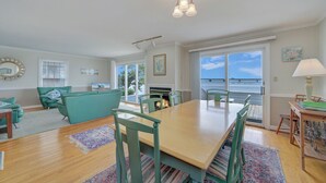 Amplia sala de estar con una mesa de comedor de madera, sillas color turquesa y una chimenea.