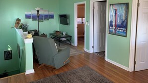 A living room with a green sofa, a coffee table, a TV, and a door leading to another room. - Relax at 3100 feet and enjoy the peace and tranquility (Free Union)