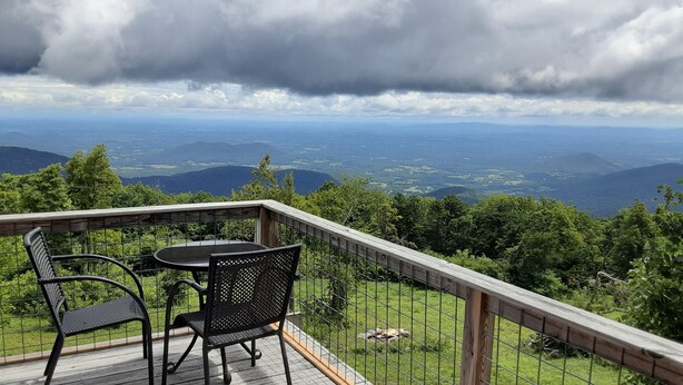 A deck with two chairs and a table overlooking a scenic landscape with mountains and a cloudy sky. - Relax at 3100 feet and enjoy the peace and tranquility (Free Union)