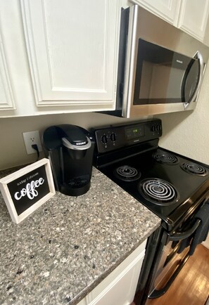 A kitchen with a coffee maker, a microwave, and a stove.