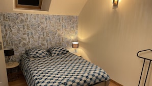 A bedroom with a patterned headboard, a bedside lamp, and a hanging light fixture. - Au 10 fontaines (Etoges)