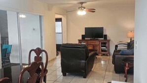 A spacious living room with a dining area, a television, and a ceiling fan. - Le Cartier 207 STR-02440 (Sunny Isles Beach)