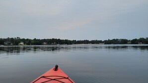 A red kayak on calm water with a tree-lined shore in the background. - 15 minutes from Base (Pemberton)