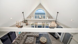 Een ruime living in loftstijl met een groot raam met uitzicht op zee, een hoge plafond en een modern design.