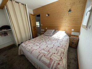 Cozy bedroom with a neatly made bed, bedside tables, and a wardrobe with mirror.