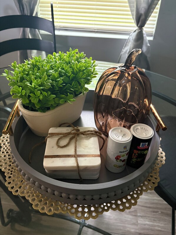 Una mesa con una planta en maceta, un calabacín, una barra de jabón y dos botes de especias McCormick.