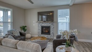 Una sala de estar moderna con chimenea, asientos cómodos y ventanas amplias.