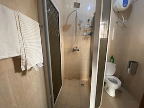 Een badkamer met douche, toilet en een handdoekhouder.