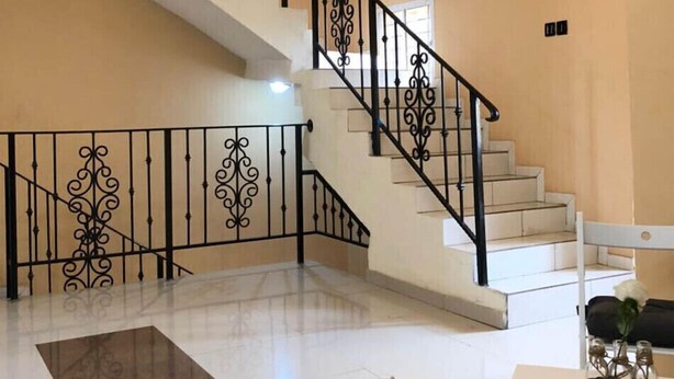 Un'ampia zona giorno con una scala, un lampadario e un tavolo da pranzo con sedie.