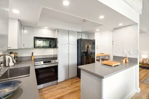 Een moderne keuken met roestvrijstalen apparatuur, witte kasten en een centraal eiland.