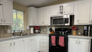 A modern kitchen with white cabinetry, a stainless steel stove, a microwave, and a coffee maker. - Relaxing Foothills Home RV Hookup and Parking (Yuma)