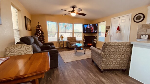 A living room with a fireplace, a television, a Christmas tree, and a ceiling fan. - Relaxing Foothills Home RV Hookup and Parking (Yuma)