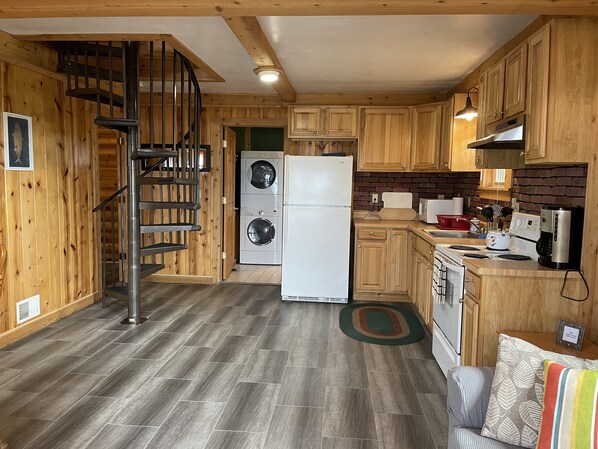 A compact kitchen with wooden cabinets, a built-in washing machine, a refrigerator, and a stove.